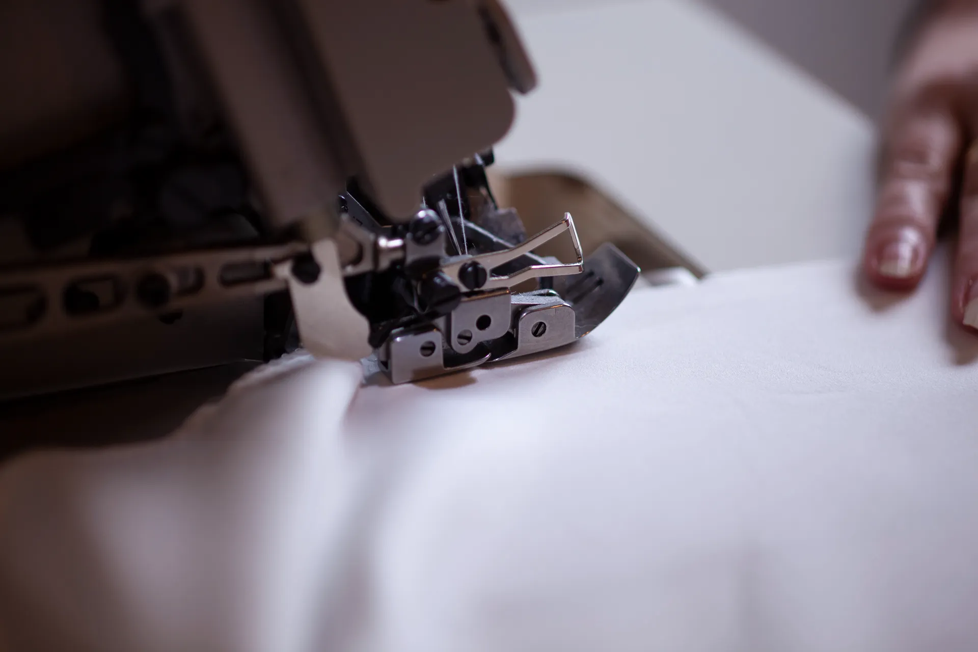 Detailbild einer Overlock-Nähmaschine mit Stoff